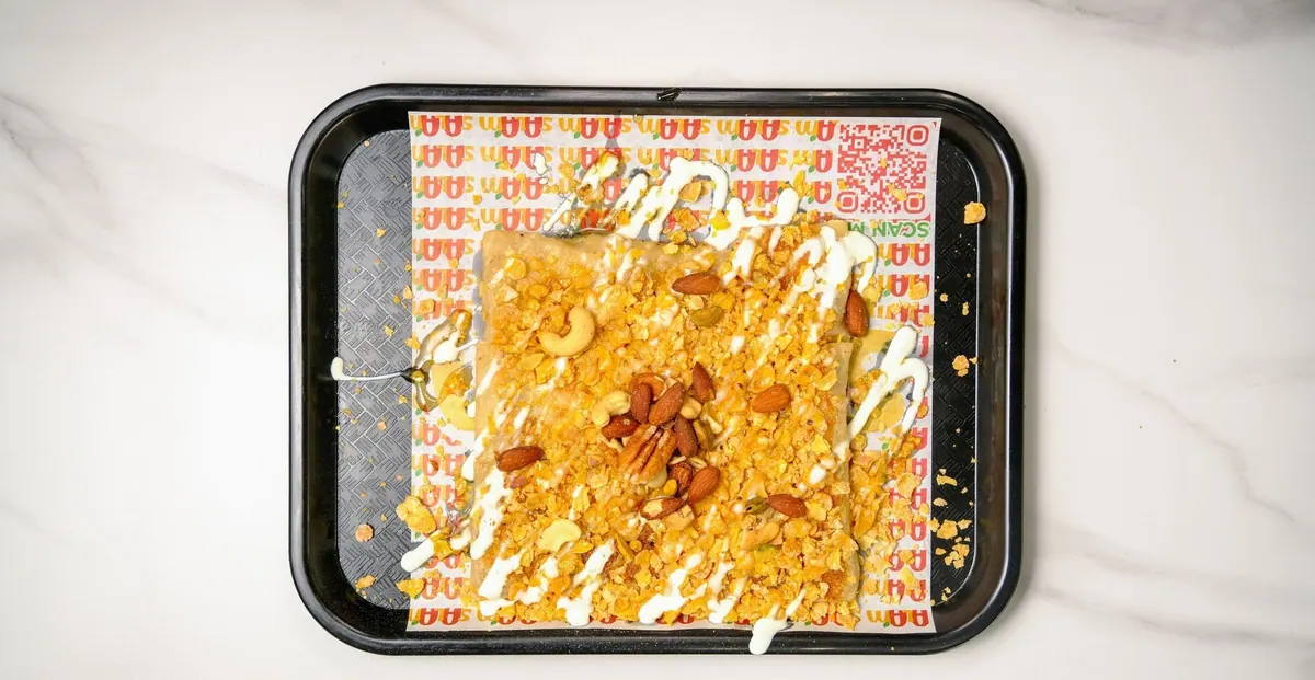 Sweet mutabbaq topped with crushed nuts, almonds and cream