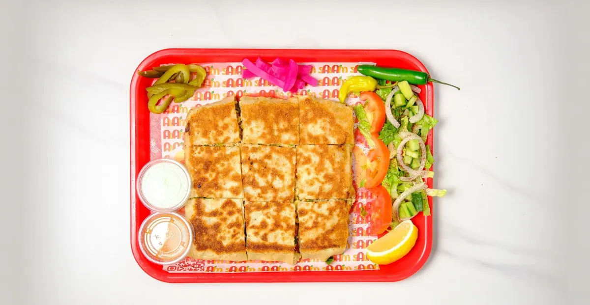 Chicken mutabbaq cut into squares with salad, pickled turnips and garlic sauce